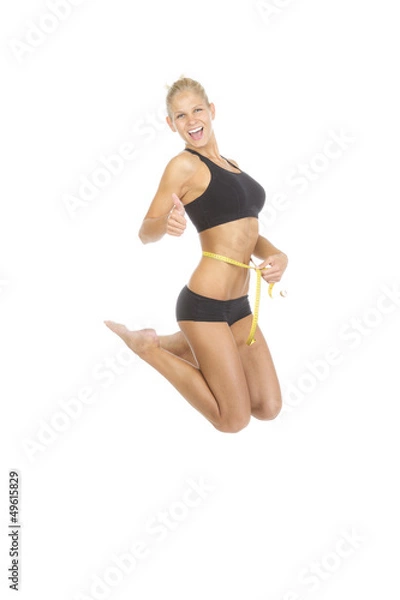 Fototapeta Frau misst ihren Bauchumfang und springt  vor Freude in die Luft