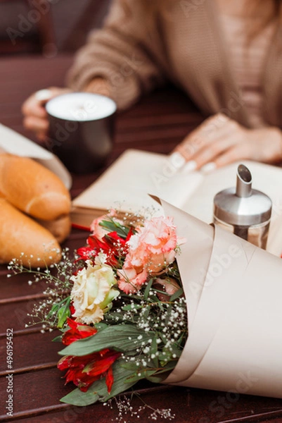 Fototapeta French clothing style, street fashion. A beautiful girl in a cardigan, red beret, and glasses walks through the old city and sits in a cafe. Spring mood and vibes