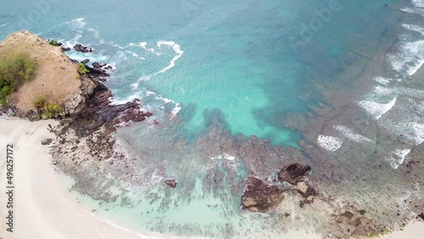 Obraz Top-down drone shot of an idyllic Koka Beach. Hidden gem of Flores, Indonesia. Beauty in the nature. Calm waves washing the cliff's slopes. Serenity and calmness. Beach surrounded by high, green hills