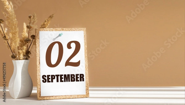 Fototapeta september 2. 2th day of month, calendar date.White vase with dead wood next to cork board with numbers. White-beige background with striped shadow. Concept of day of year, time planner, autumn month