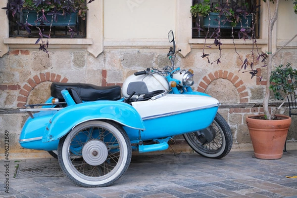 Fototapeta Unusual vehicle blue  vintage restored motorcycle in the historical center of the city against the background of an ancient building