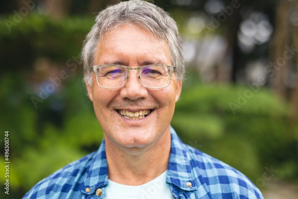 Fototapeta Portrait of smiling caucasian senior man standing in backyard on weekend