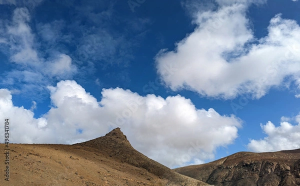 Fototapeta Dry inland mountains of the island of Fuerteventura in the Canary Islands under a blue cloudy sky.