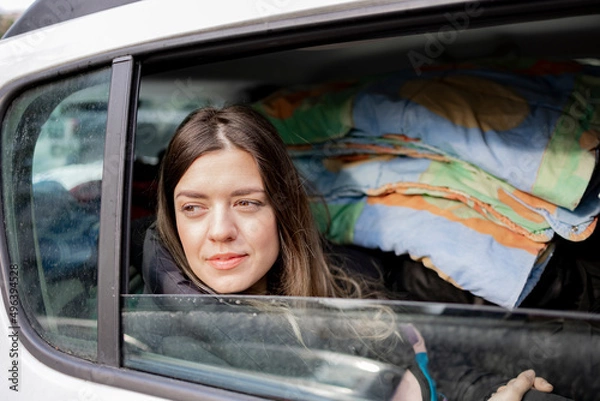 Fototapeta Getting a university in a city different from the city you live in. College young girl is going to another city to study. Her family takes her to that city. Back of car is full of stuff. She is sad.