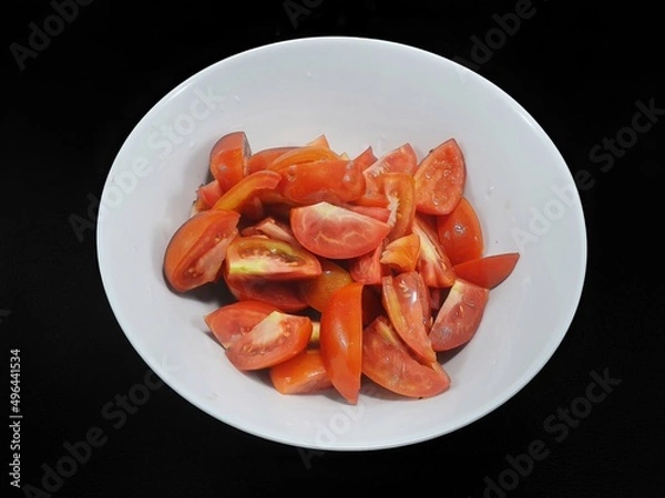 Obraz Top view of tomatoes sliced in white bowl isolated on black background (Solanum lycopersicum var. cerasiforme), Ready to eat or cooking
