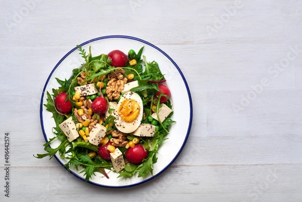 Obraz Green salad with tofu and chia seeds. Mixed salad with tofu hazelnuts and tofu on rustic table. Fresh diet salad served in plate.