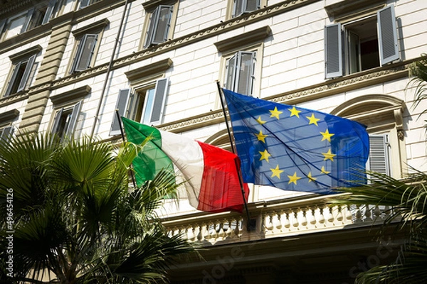 Fototapeta Italian and EU flag flags with old houses in the background