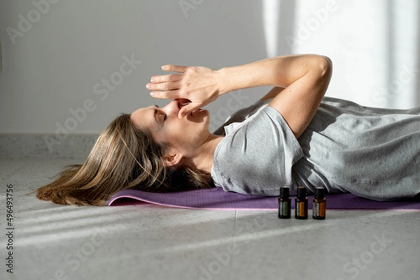 Fototapeta woman meditates with essential oils while lying on a yoga mat. Ultrasonic and humidifying aromatherapy. Meditation fitness and exercise concept copy space. Active lifestyle. home or gym club