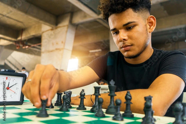Fototapeta Latin young man practicing chess techniques in a basement. Concept of intellectual development in the millennial youth of Nicaragua, Central America and South America.