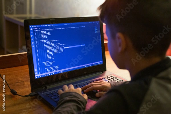 Obraz Young boy coding on laptop at night