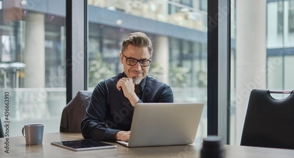 Fototapeta Businessman using laptop computer in office. Happy middle aged man, entrepreneur, small business owner working online.