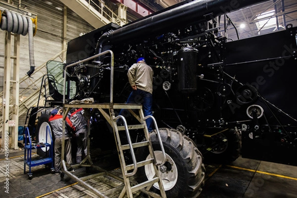 Obraz Industrial workers assembles agricultural harvester in workshop