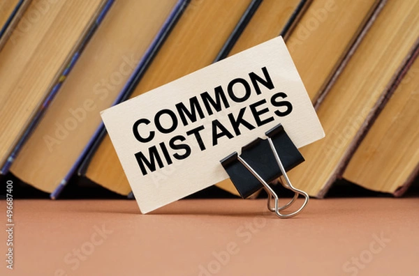 Fototapeta On the table against the background of books is a business card with the inscription - Common Mistakes