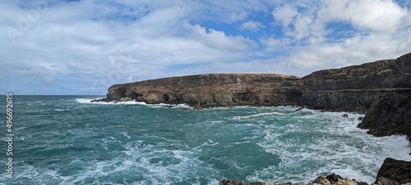 Fototapeta Rocky cliffs at Ajuy on the island of Fuerteventura part of the Canary Islands with a choppy turquoise sea and a cloudy sky
