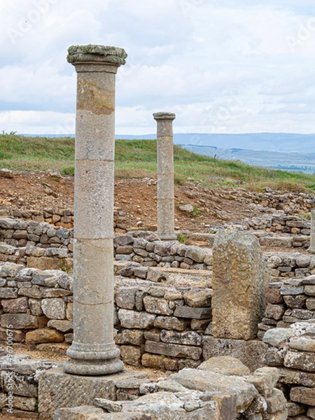 Fototapeta Ruinas celtíberas en Numancia, con piedras, formas, y columnas a lo largo del paisaje con cielo azul, verano de 2021.
