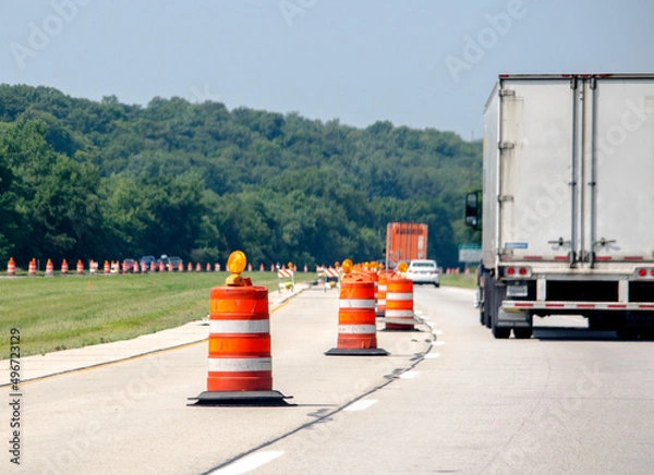 Obraz Highway construction season with traffic going past orange traffic cones