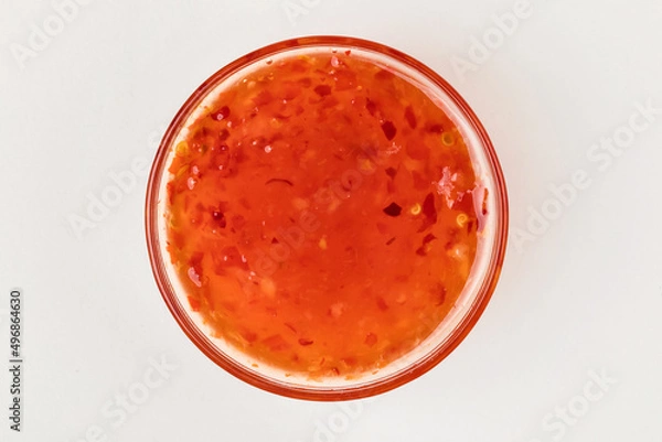 Fototapeta A cup with sweet chili sauce. White background. Top view.