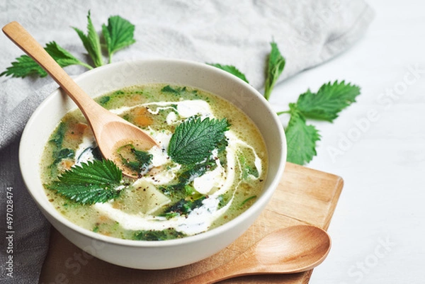 Obraz Vegan nettle soup on rustic wooden table. Healthy vegan nettle soup served in bowl on rustic wooden table.