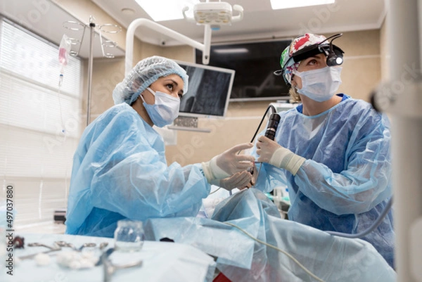 Fototapeta Surgeons operating on a man looking into a screen of health vital signs