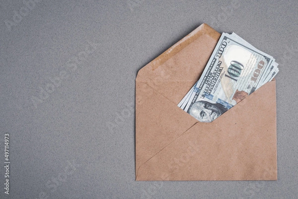 Fototapeta Dollar bills in a paper envelope on a gray background. Bonus, reward, benefits concept