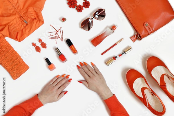 Obraz Women's hands with manicure and items of women's clothing and accessories in orange on a white background.