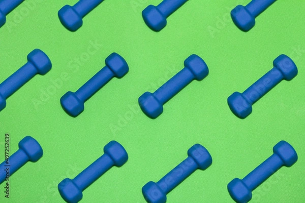 Obraz Rows of blue dumbbells on bright green gym mat 