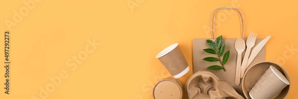 Fototapeta Banner with eco-friendly tableware - kraft paper food utensils, paper containers and cups, drinking straws and wooden cutlery on orange background with copy space. Sustainable food paper packaging