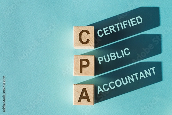 Fototapeta Wooden cubes building word CPA - abbreviation of certified public accountant - with shadows on light blue background.