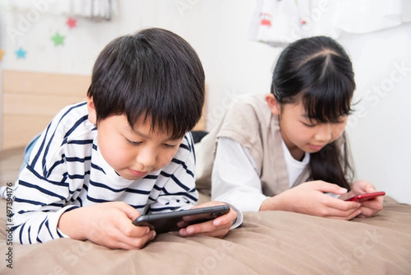 Fototapeta 子供部屋でスマホを見ているアジア人の子供