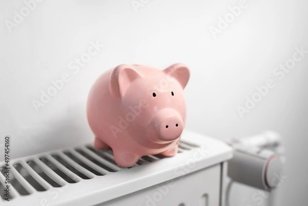 Obraz heating, energy crisis and consumption concept - piggy bank on radiator at home