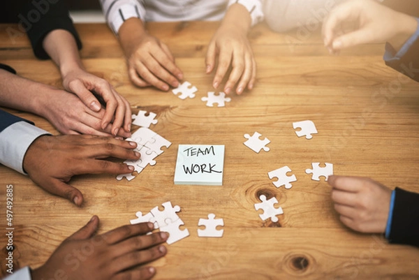 Fototapeta Planning it all out, piece by piece. High angle shot of a group of unrecognizable coworkers building a puzzle on their boardroom table.