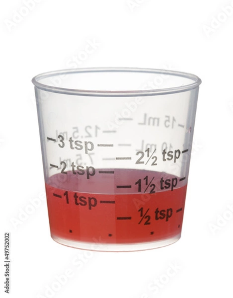 Fototapeta Cold or cough syrup medicine in a measuring cup isolated on whit