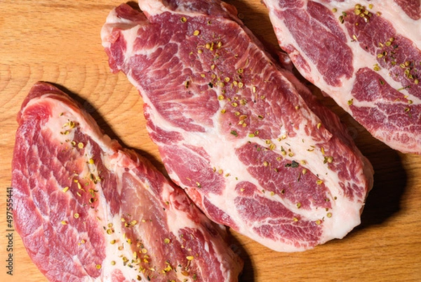 Obraz Sliced raw pork meat  with spices on wooden surface, top view