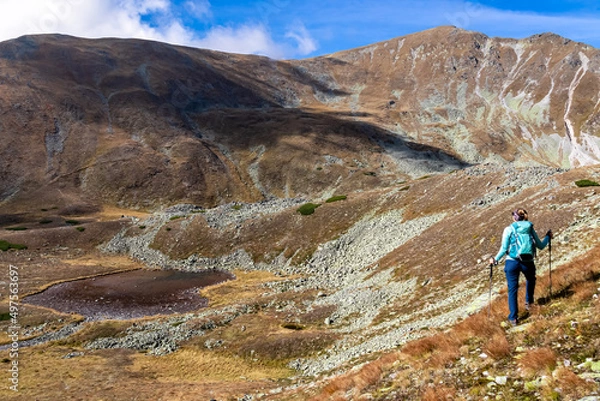 Fototapeta Woman with backpack and view on Haemerkogel in the Lower Tauern mountain range, Styria, Austria, Europe. Sunny autumn day in Seckau Alps. Scenic hiking trail to Seckauer Zinken on dry, bare terrain