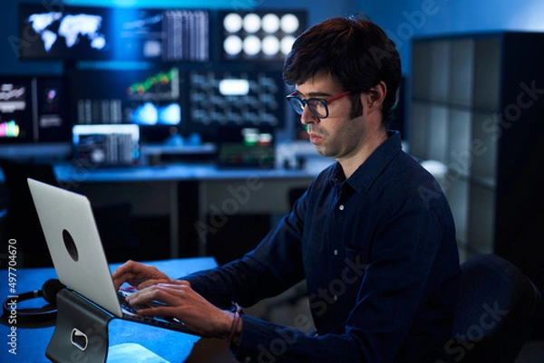 Fototapeta Broker Trader Business Man Working on Laptop in a Corporate Office. Multiple Monitors at Background
