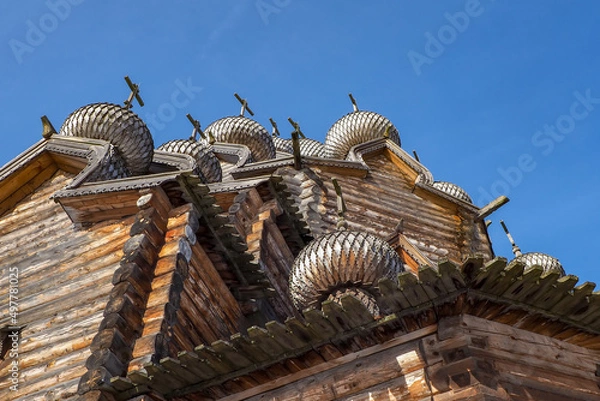 Fototapeta a fragment of the walls of a wooden church with domes on a blue sky background