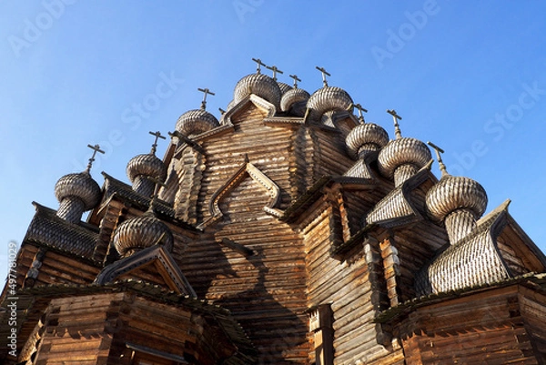 Fototapeta a fragment of the walls of a wooden church with domes on a blue sky background