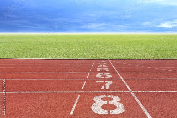 Fototapeta Running track number in front of tracks and stadium with blue sk