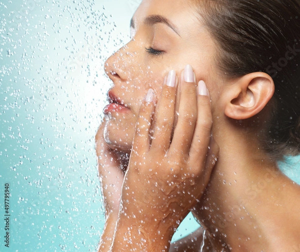 Fototapeta You are rare, luminous, and valuable. Shot of a young woman taking a shower against a blue background.