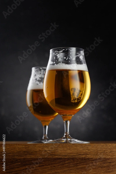 Fototapeta Two glasses of light beer on dark background. Selective focus