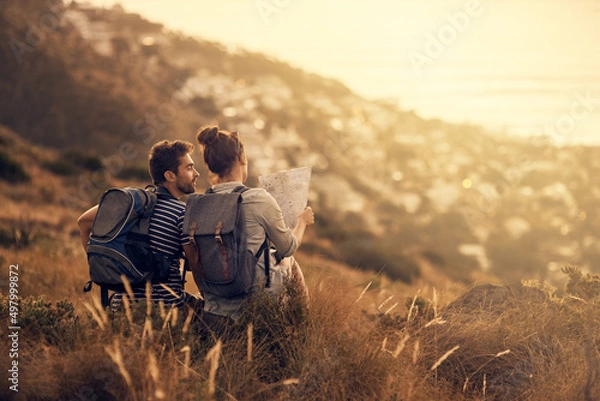 Fototapeta Youll never regret a day outdoors. Rearview shot of a couple looking at a map while taking a break from hiking.
