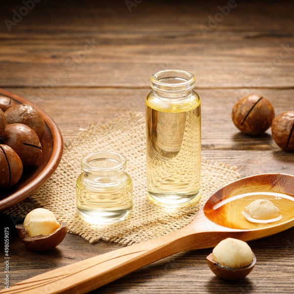 Fototapeta Macadamia oil and Macadamia nuts on a wooden background. Natural vitamins.