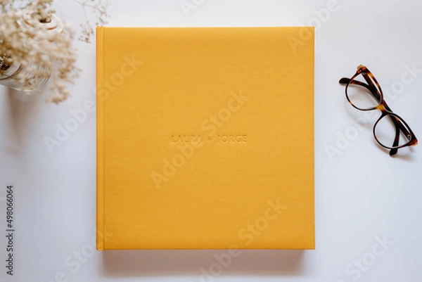 Obraz Composition with a wedding or family photo album, made of natural yellow linen fabric on a white background. Flat lay, top view still life.