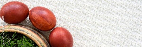 Obraz Panoramic photo. Top view of easter eggs, lying on a lace tablecloth. Painted brown. Fresh green oats grass.