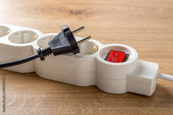 Obraz Unplugged electric appliance plug over switched off white power strip on the floor. Power crisis. Increasing the energy costs, heating costs, save electricity concepts. Power outage.