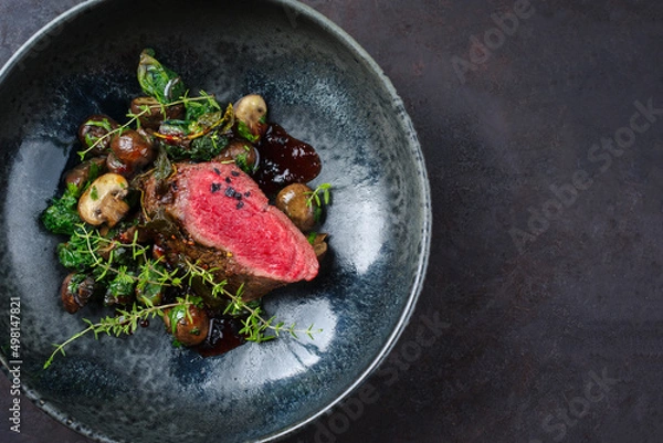 Fototapeta Modern style traditional fried dry aged angus beef filet medaillons natural with mushrooms and kalette in red wine sauce served as top view on a design plate with copy space
