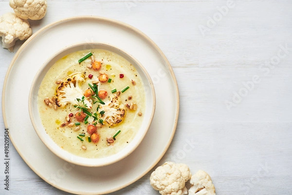 Obraz Vegan cauliflower soup on white background. Healthy vegan cauliflower soup served in bowl on white table.
