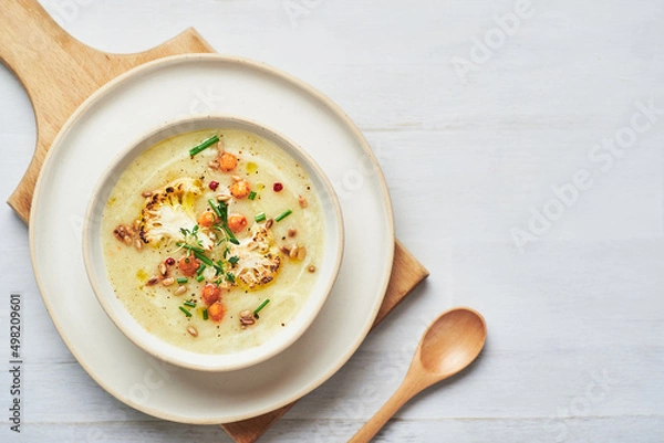 Obraz Vegan cauliflower soup on white background. Healthy vegan cauliflower soup served in bowl on white table.