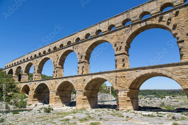 Fototapeta Famous Pont du Gard - an iconic Ancient Roman bridge, aqueduct and engineering masterpiece in the region Provence, France. It is formed by three floors of arcades, massive arches and pillars