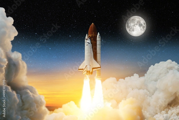 Fototapeta Spaceship lift off. Space shuttle with smoke and blast takes off into space on a background of a sunset with a full moon and stars in the sky. Elements of this image furnished by NASA.